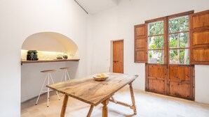 Una cocina con una mesa de madera, taburetes, una ventana y una puerta.