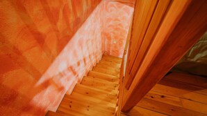 A wooden staircase leading to a room with a textured orange wall.