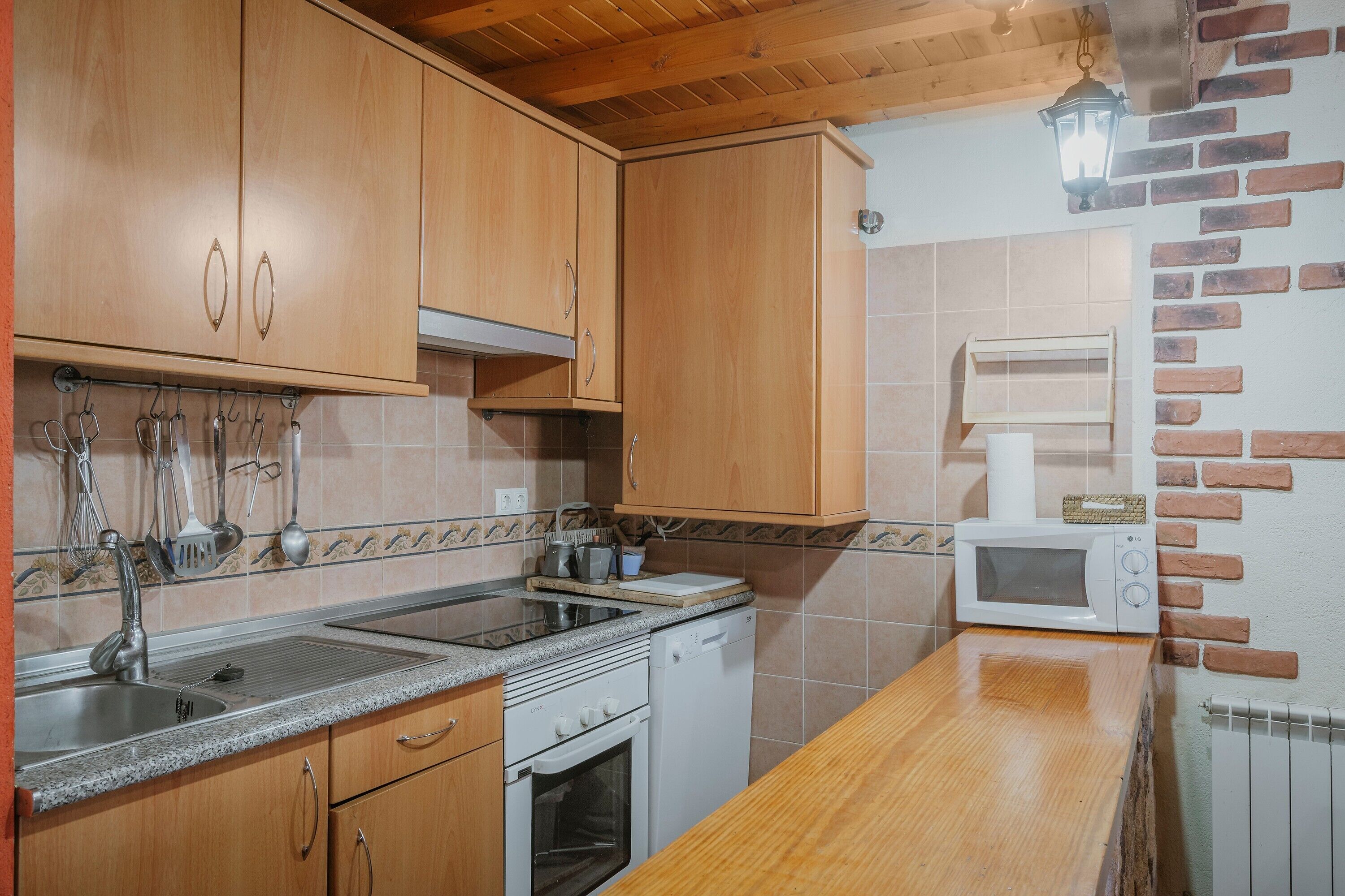A kitchen with wooden cabinets, a microwave, a stove, and a sink.