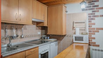 A kitchen with wooden cabinets, a microwave, a stove, and a sink.