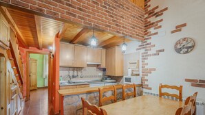 A kitchen with wooden cabinets, a dining table, and hanging lights.