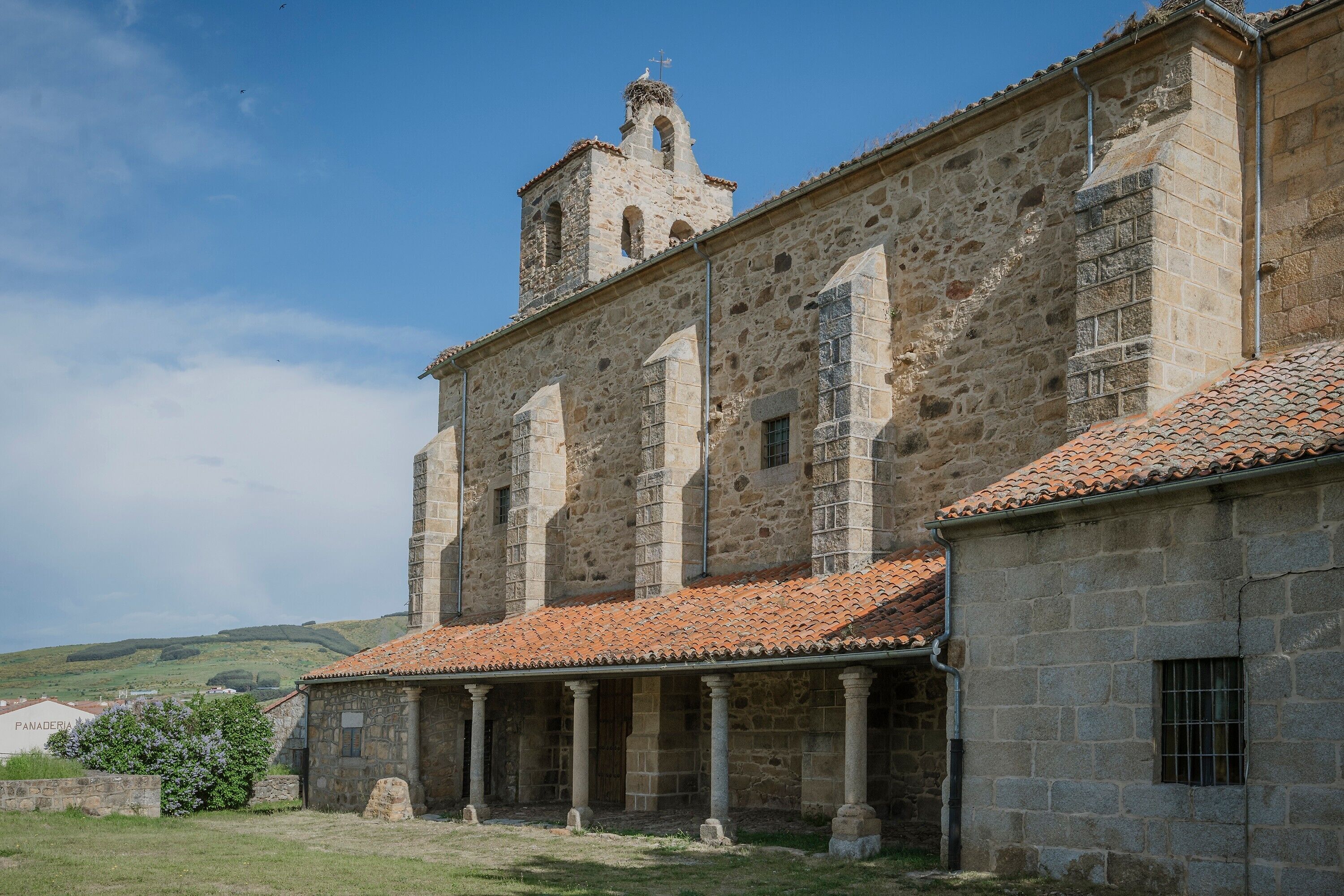 A stone building with a bell tower, columns, and a tiled roof.
