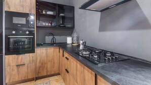 A modern kitchen with wooden cabinets, a built-in oven, a stove, and a microwave. - 'Canarian Retreat' with Sea Views, Private Terrace and Wi-Fi (Santa Brigida)
