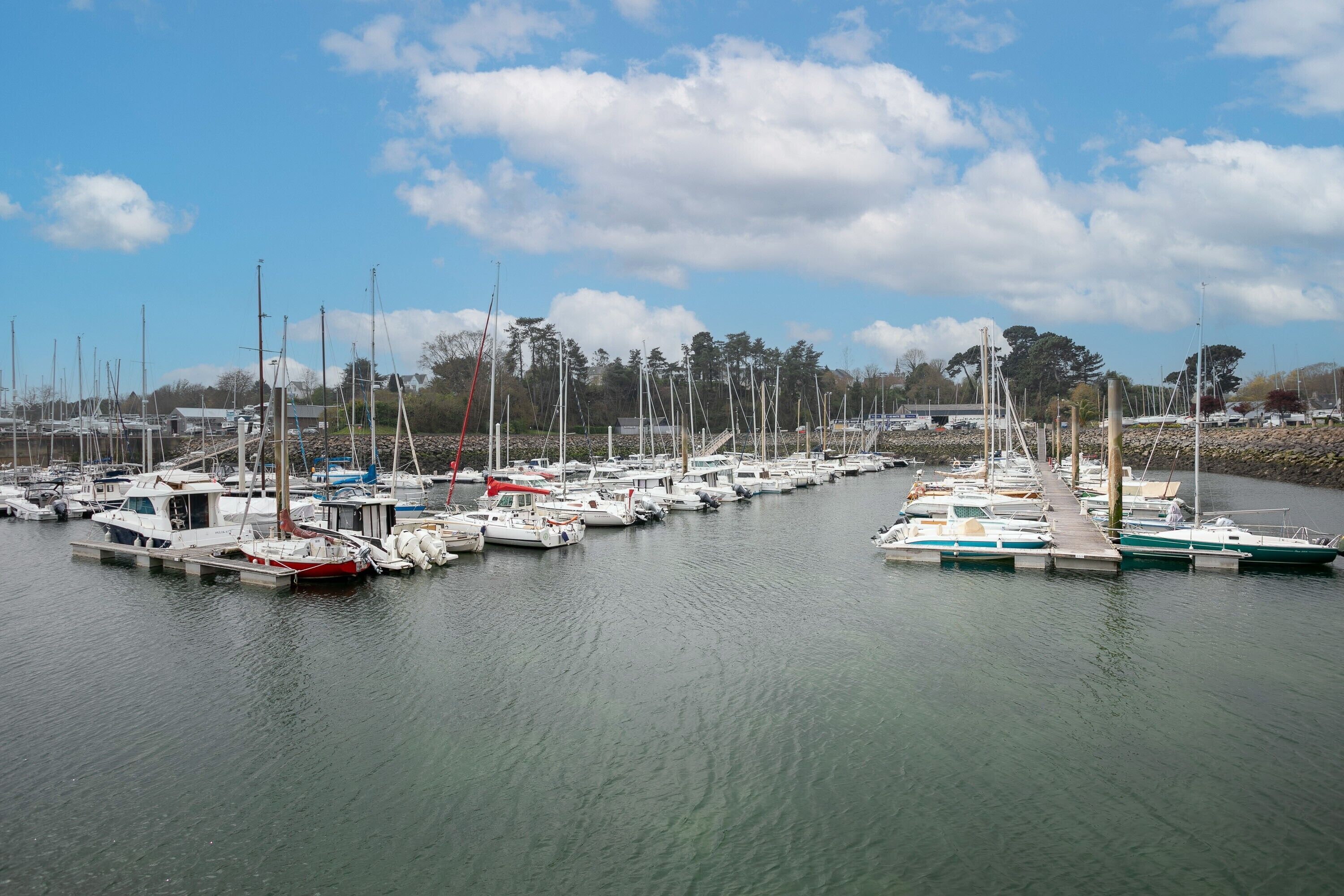 Un port de plaisance où sont amarrés de nombreux bateaux, avec une eau calme et un ciel dégagé.