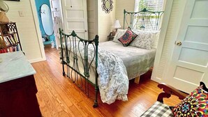 Un dormitorio con cama, una silla, un escritorio y un armario.