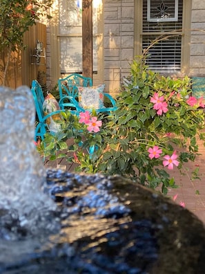 Un espace patio agrémenté d’un mur en pierre, d’une porte en bois et d’une chaise bleue avec un coussin.