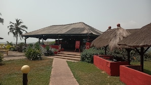 A building with a thatched roof and a covered outdoor area with steps leading to the entrance. - beach resort casa (Sekondi-Takoradi)