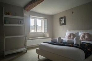 Un dormitorio con cama, ventana, radiador y estantería.