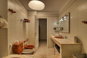 Ein schmales Badezimmer mit Toilette, Waschbecken und Spiegel.
