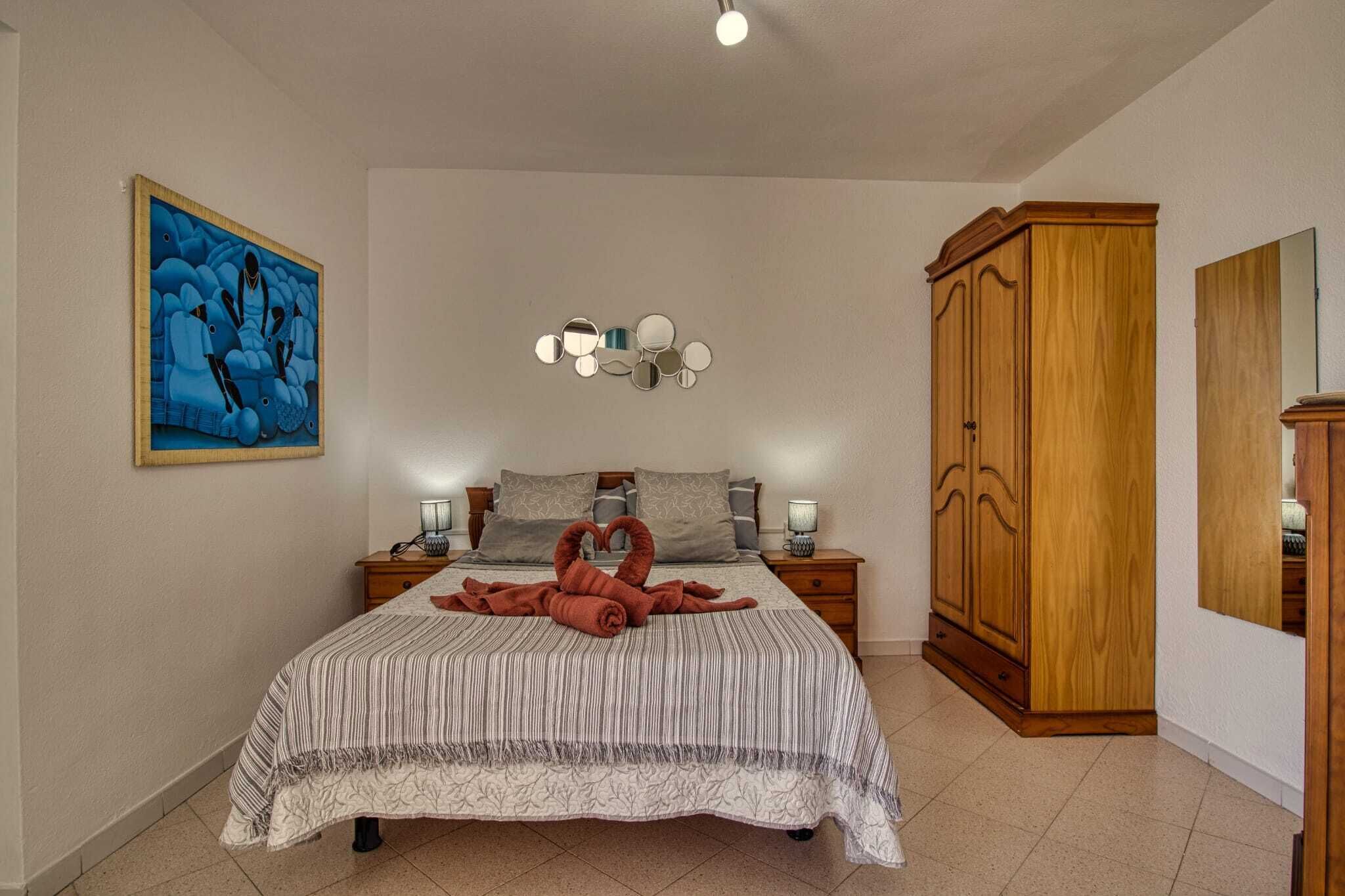 Una camera da letto con un letto, comodini, un armadio, un quadro e una lampada a parete.