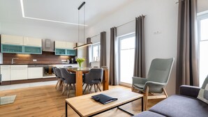 Ein modernes Wohnzimmer mit Couchtisch aus Holz, grauem Sofa und einem Essbereich mit Holztisch und Stühlen.