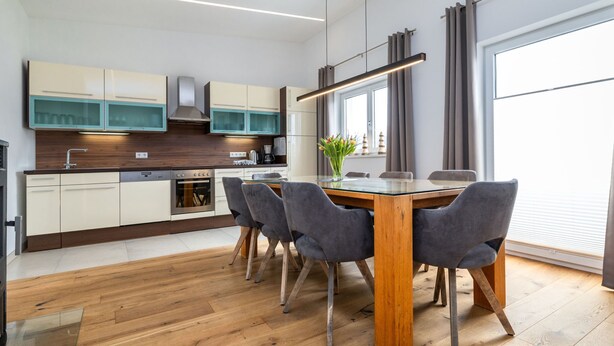 Eine moderne Küche mit Essbereich, Holzboden und einem großen Fenster.