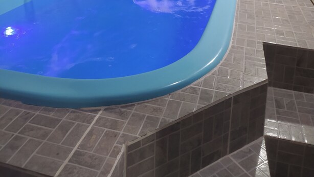 Un petit bain à remous rectangulaire, de couleur bleue à l’intérieur, entouré de carreaux de couleur beige.
