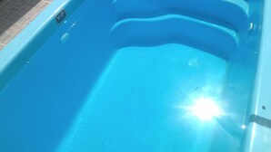 Une piscine aux parois intérieures bleues, entourée de murs recouverts de carreaux.