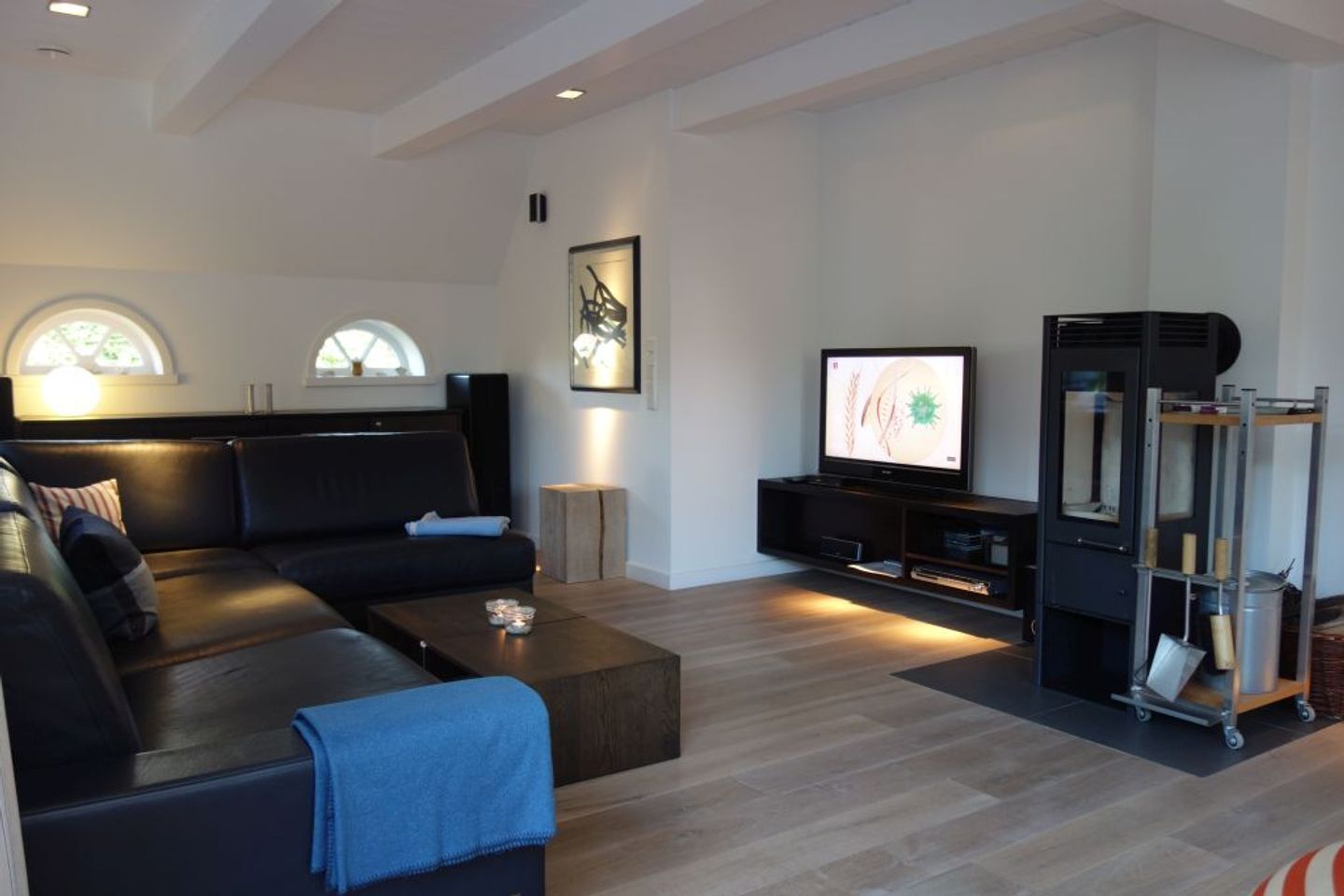 A modern living room with a dark sofa, a coffee table, a TV, and a built-in fireplace.