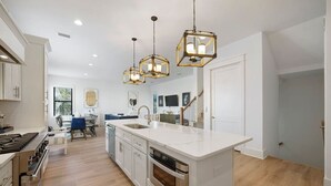 A modern kitchen with a central island, stainless steel appliances, and pendant lighting. - Get Busy Livin! on 30A (Santa Rosa Beach)