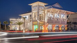 A hotel with a prominent tower, outdoor seating area, and a well-lit facade. - Get Busy Livin! on 30A (Santa Rosa Beach)