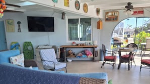 Un espacio de estar al aire libre techado con un sofá azul acolchado, mobiliario de mimbre y una mesa de comedor con sillas.