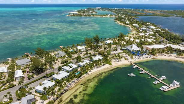 Ein Luftbild eines Küstenresorts mit mehreren Gebäuden, einer Marina und klarem, türkisblauem Wasser.