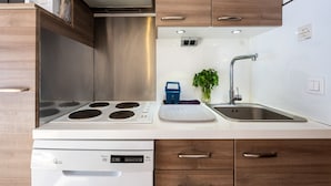 A modern kitchen with a built-in stove, a sink, and wooden cabinets. - Apartment in Morillon near Ski Slopes (Morillon)