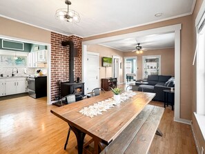 A spacious living area with a long wooden dining table, a fireplace, and a modern kitchen in the background. - Quaint Cottage in downtown Cascade (Cascade)