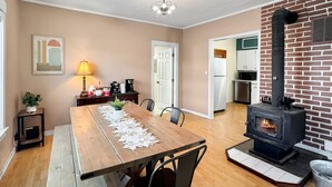 Een eetgedeelte met een houten tafel, stoelen, een lamp en een open haard.