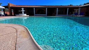 A clear swimming pool with a tiled roof and a white column structure.