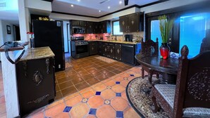 A modern kitchen with a black refrigerator, stainless steel appliances, and a patterned tile floor.