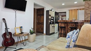 A living room with a TV, a guitar, a coffee table, and a sofa. - Aeolian Residence (Provincia de Guanacaste)