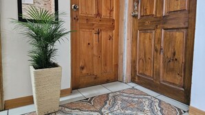 A wooden door with a textured mat and a potted plant beside it. - Aeolian Residence (Provincia de Guanacaste)