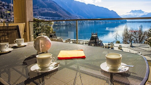A table with a view of a lake and mountains.