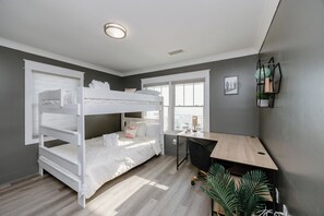 Cozy retreat with a bunk bed, desk, and chair, plus a large window and a small potted plant.