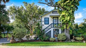 A two-story house with a balcony, surrounded by lush greenery and palm trees. - Uptown Classic 1 | Effortless Exploration of STA (St. Augustine)