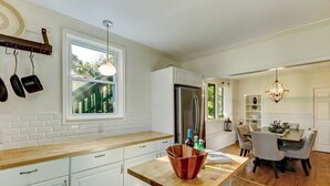 A modern kitchen with white cabinets, a wooden countertop, and a dining area with a table and chairs.