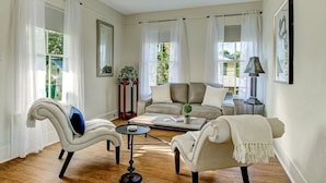 Un salon spacieux comprenant un canapé, deux fauteuils, une table basse et un ventilateur de plafond.