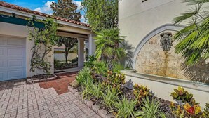 A residential property with a garage, a covered patio, and a landscaped garden with various plants.