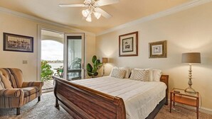 A bedroom with a large bed, a chair, a nightstand, and a ceiling fan.