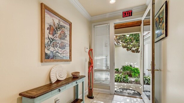 A hallway with a wooden console table, a framed painting, and an exit sign.