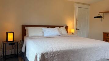 A neatly made bed with a patterned bedspread, a bedside lamp, and a nightstand with a lamp.