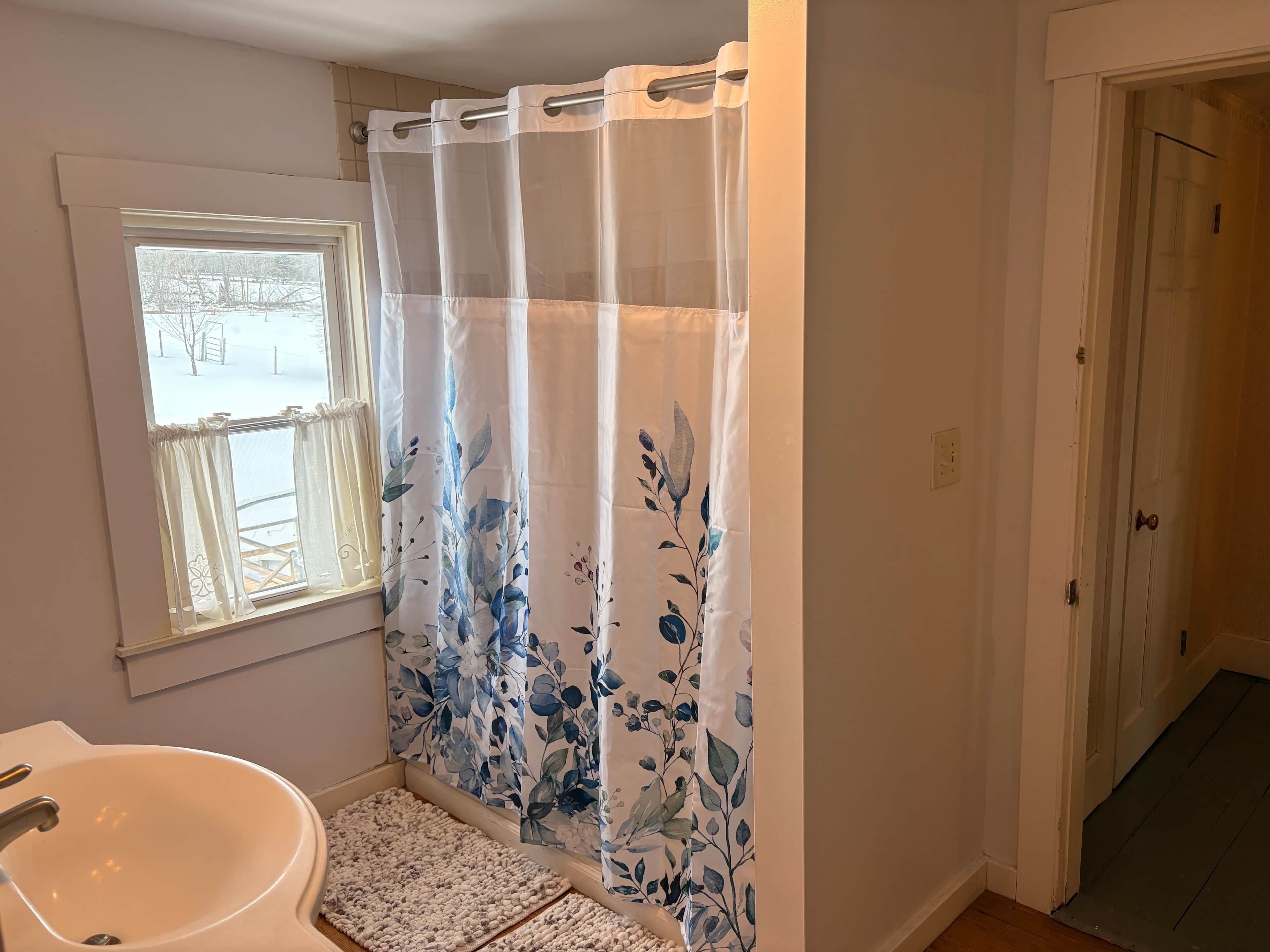 A bathroom with a bathtub, a window, and a door.