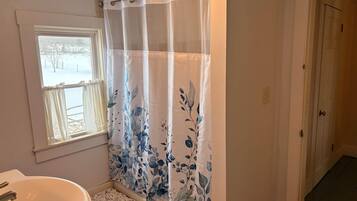 A bathroom with a bathtub, a window, and a door.