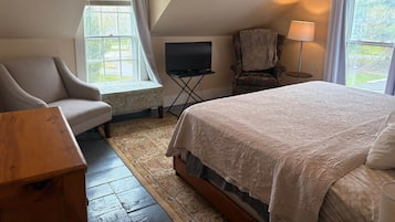 A bedroom with a bed, a chair, a television, and a lamp.