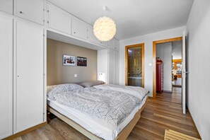Ett sovrum med en säng, en garderob och en hängande lampa.
