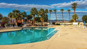 Ein Swimmingpool mit Liegestühlen und Palmen.