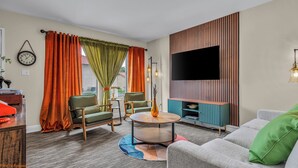 Ein modernes Wohnzimmer mit Sofa, Sesseln, Couchtisch, Flachbildfernseher und einer Holz-Unterhaltungseinrichtung.