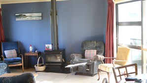 A living room with a fireplace, a blue wall, and a window with curtains.