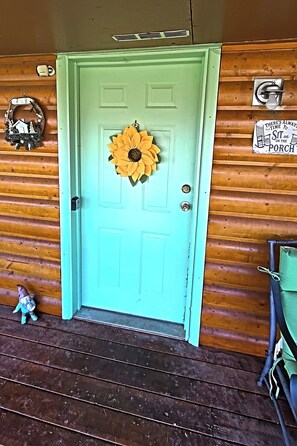 A teal door with a sunflower decoration, a small figurine, and a sign on the wall.