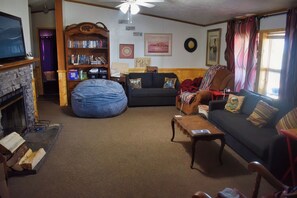 A living room with a fireplace, a bookshelf, a sofa, and a coffee table. - Enchanting cabin with WiFi in Tabiona - 3 bedrooms (Tabiona)