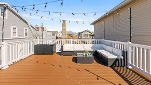 A rooftop deck with a white railing, a gray sofa, and a small table. - 4BR Home w/ Rooftop Deck - 3 Block to Beach (Ventnor City)