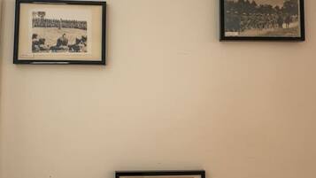 Three framed items on a wall: a black and white photograph of a crowd, another black and white photograph of a landscape, and a framed document.